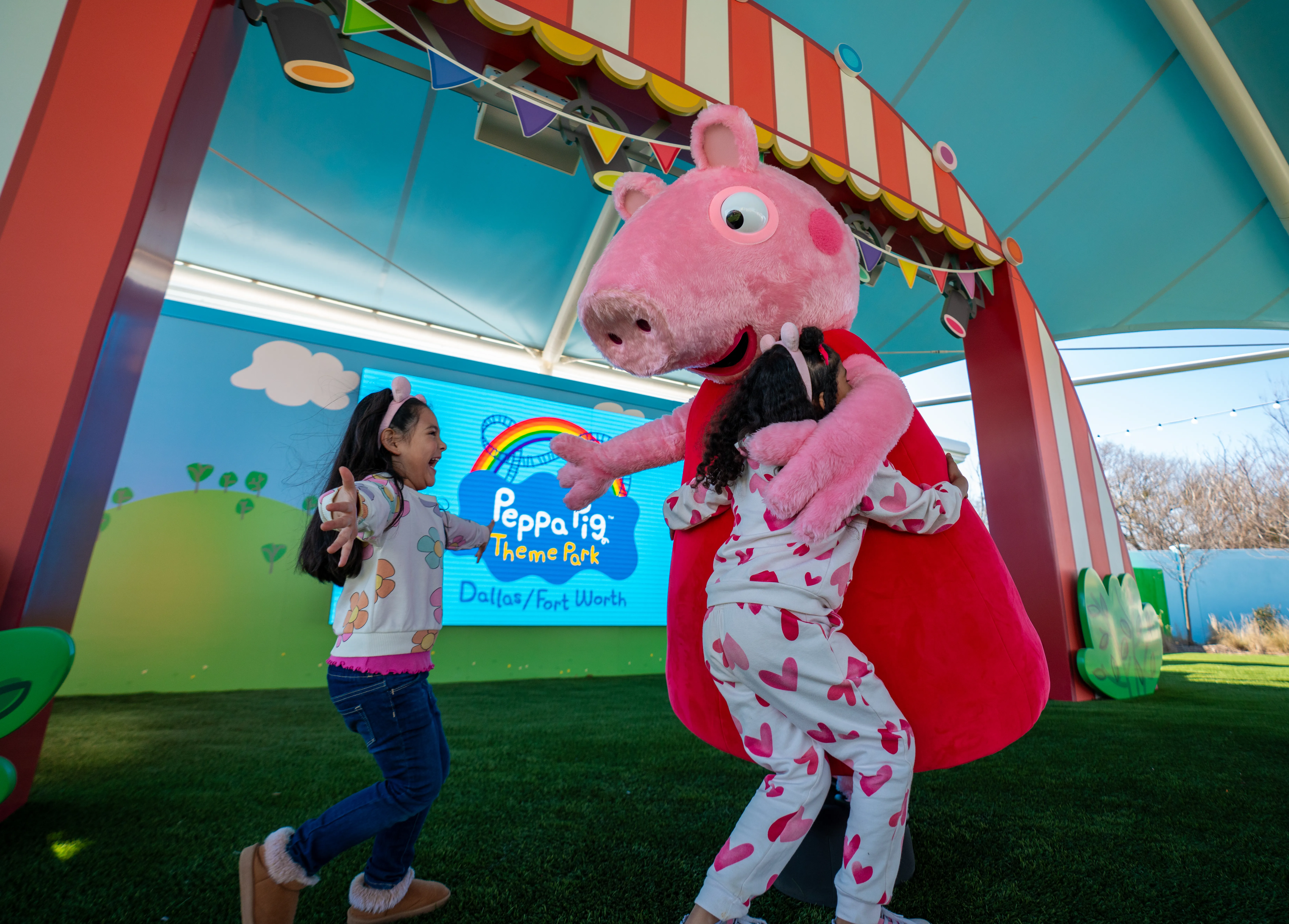 Two children running up to hug Peppa Pig at her meet and greet