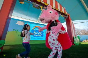 Two children running up to hug Peppa Pig at her meet and greet
