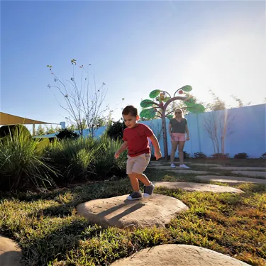 A mother and son play together at Madame Gazelle's Nature Trail attraction at Peppa Pig Theme Park in Dallas Fort Worth. They enjoy exploring the colorful and interactive nature trail, discovering fun features while surrounded by the vibrant, outdoor atmosphere of the park.