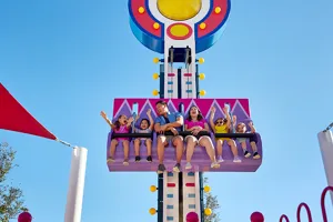 Children and parents enjoy Mr. Bull's High Striker ride at Peppa Pig Theme Park in Dallas Fort Worth. The excited families are lifted up and down in the playful ride, experiencing the fun and thrill of this interactive attraction.