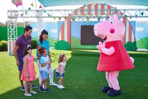 A family meets Peppa Pig at the Showtime Arena in Peppa Pig Theme Park, Dallas Fort Worth. The children excitedly pose for a photo with their favorite characters, creating memorable moments in the fun-filled atmosphere of the park.