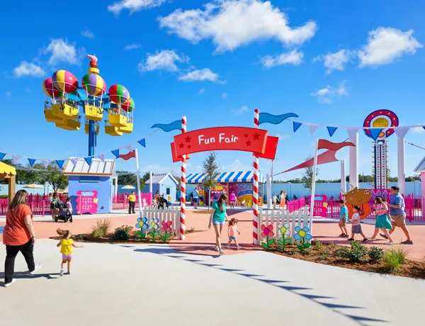 Los visitantes disfrutan de la atracción Fun Fair en Peppa Pig Theme Park en Dallas Fort Worth, jugando a diversos juegos y montando las emocionantes atracciones. La risa llena el aire mientras las familias viven la atmósfera juguetona y colorida del parque, creando recuerdos divertidos juntos.