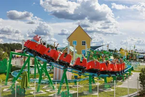 Visitors enjoy riding Daddy Pig's Rollercoaster at Peppa Pig Theme Park in Dallas Fort Worth. The excited riders smile and laugh as they experience the thrilling twists and turns of the rollercoaster, surrounded by the vibrant and playful atmosphere of the park.