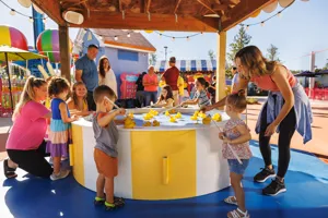 Las familias disfrutan jugando en la atracción Fun Fair en Peppa Pig Theme Park en Dallas Fort Worth. Los niños prueban su suerte al recoger patitos en el Lucky Duck Pond, rodeados por el colorido y festivo ambiente del parque.