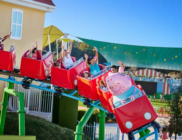 Los visitantes disfrutan de la emoción de la montaña rusa de Daddy Pig en Peppa Pig Theme Park en Dallas Fort Worth, sonriendo y riendo mientras viven juntos la emocionante experiencia.