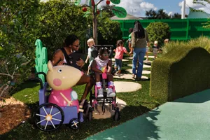 Families enjoy exploring Madame Gazelle's Nature Trail attraction at Peppa Pig Theme Park in Dallas Fort Worth, engaging with the colorful, interactive features in a lively outdoor setting.