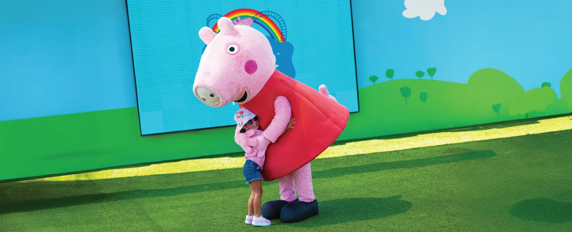 A young girl hugging Peppa Pig at PEPPA PIG Theme Park Florida